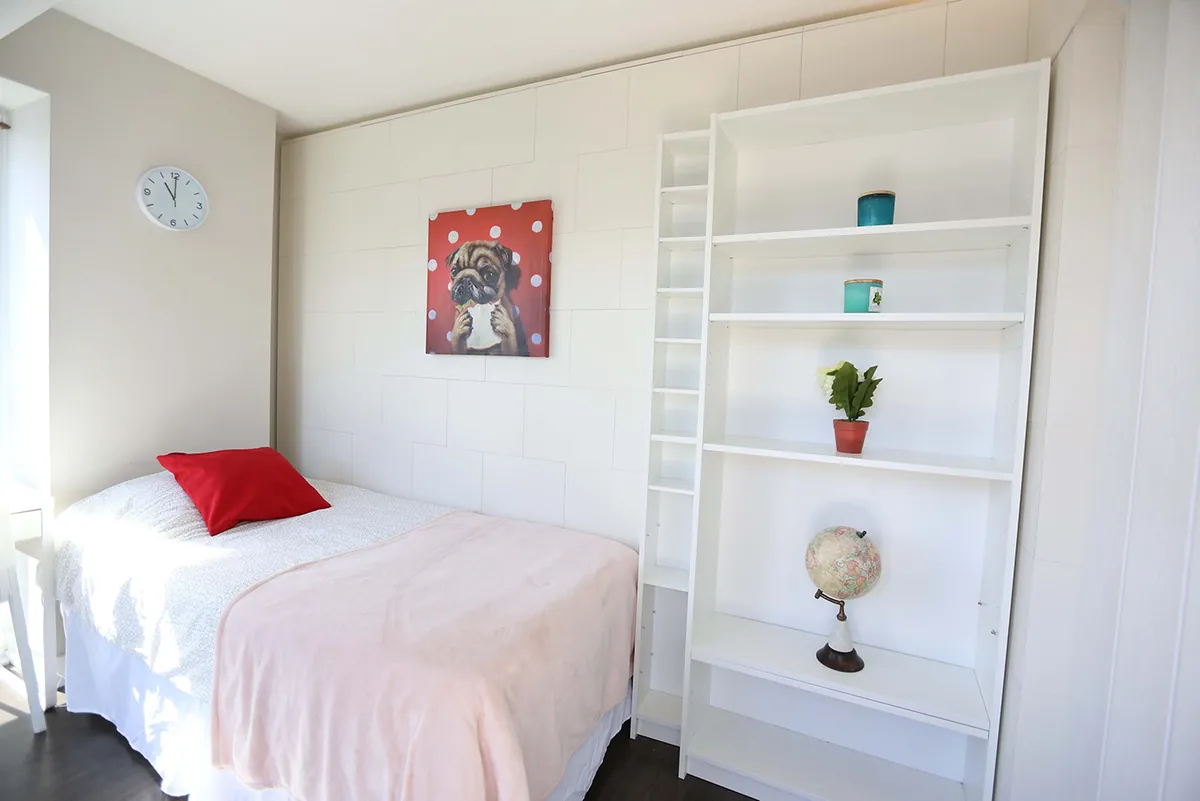 Flex sleeping area with a twin bed and a full wall of shelving